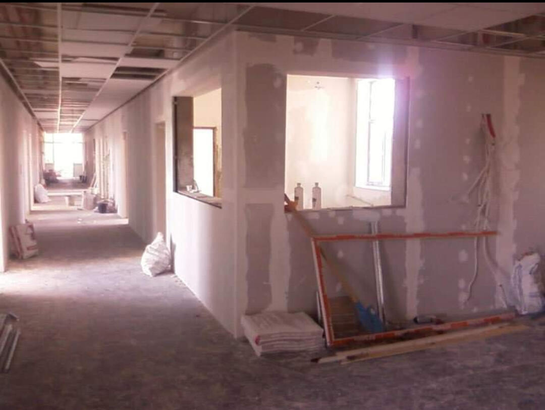 Gipsplaten afwerking kantoorruimte Gent — S GYPFIX Verlaagd gipsplaten plafond in lange hal of gang met verlichting - S GYPFIX in Gent